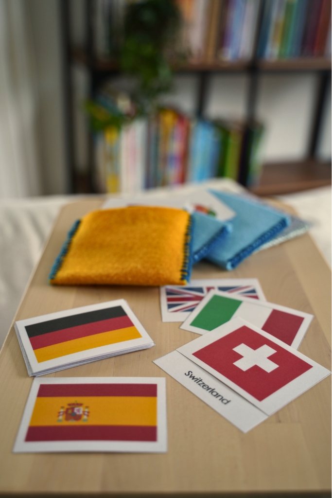 Cards of various country flags resting on a table in front of a bookshelf