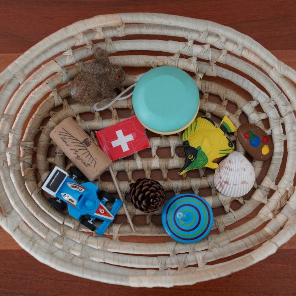 A woven basket on a table with multiple small objects used for a Montessori activity.