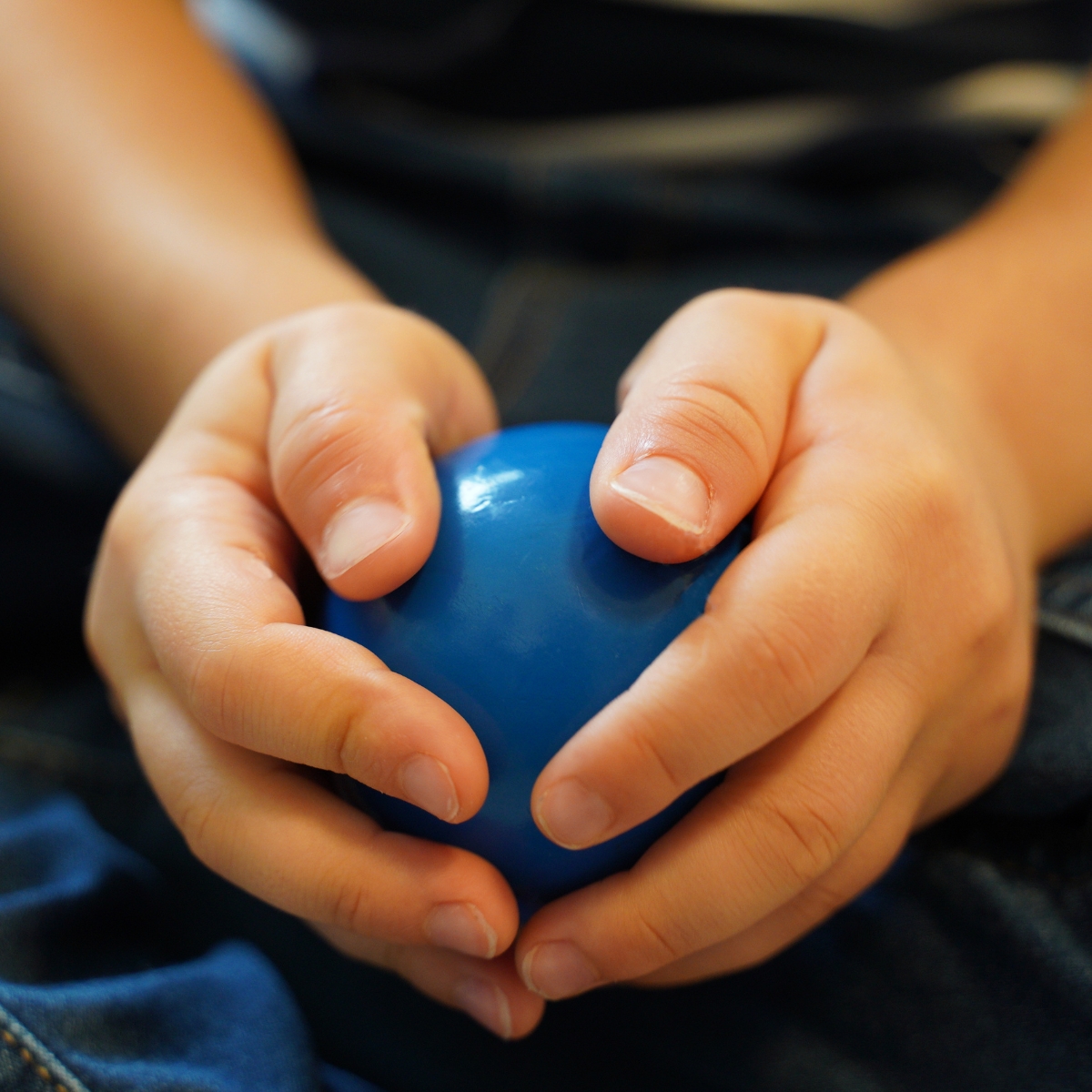 Child holding a blue Montessori sensorial sphere for tactile exploration