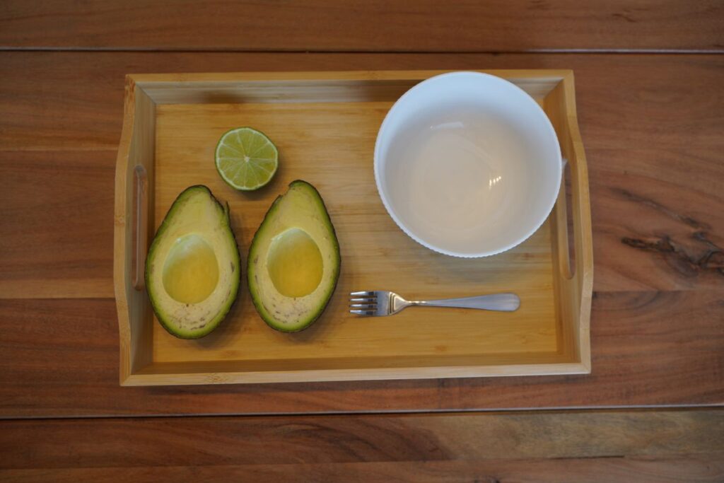 Montessori avocado preparation tray with halved avocado, lime, bowl, and fork for practical life food preparation.