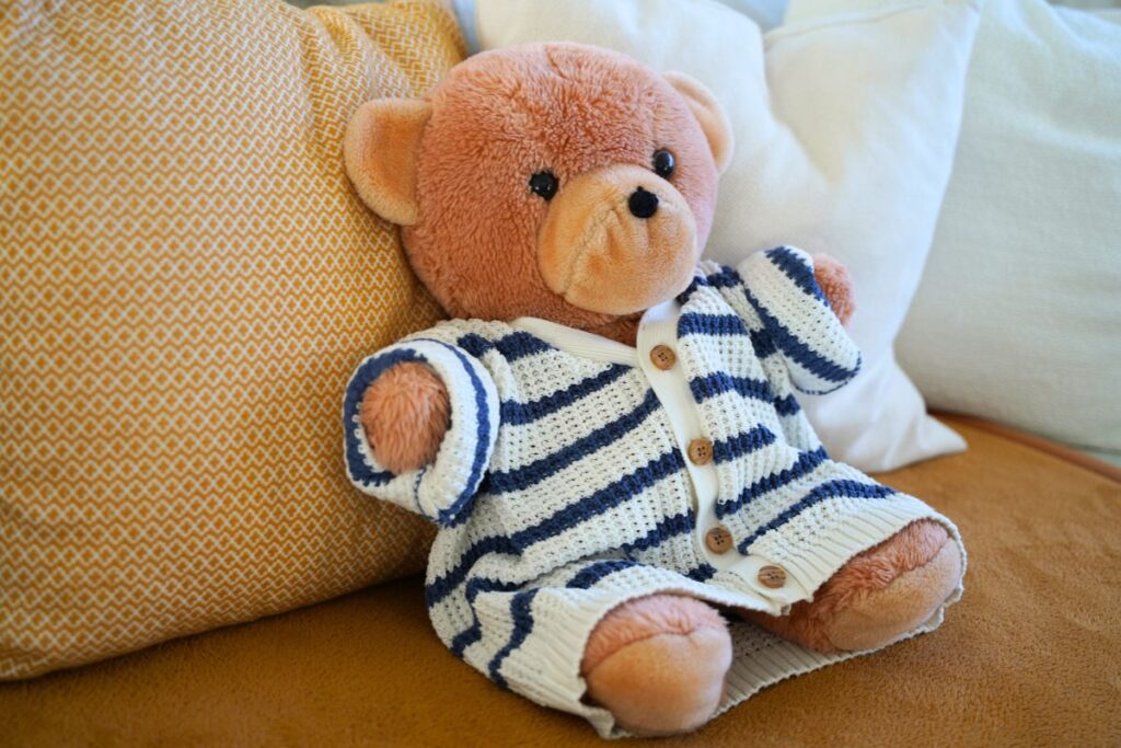 Montessori practical life dressing frame activity with large buttons, featuring a teddy bear wearing a button-up cardigan to support fine motor skills and independent dressing for toddlers